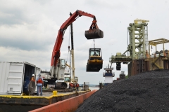 C&B using its excavator to lower a skid steer into a coal barge for unloading